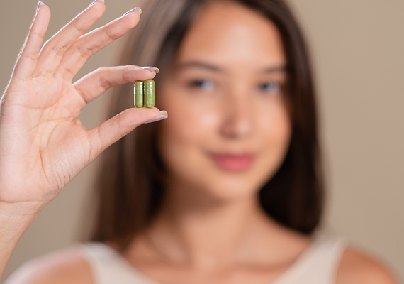 Woman holding supplement capsule